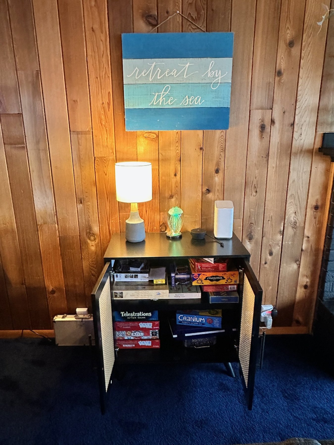 "Retreat by the Sea" sign above a cabinet stocked with board games