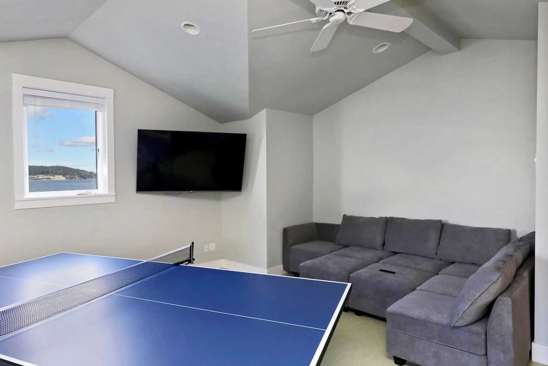 Ping pong room with sectional couch, TV, and water view